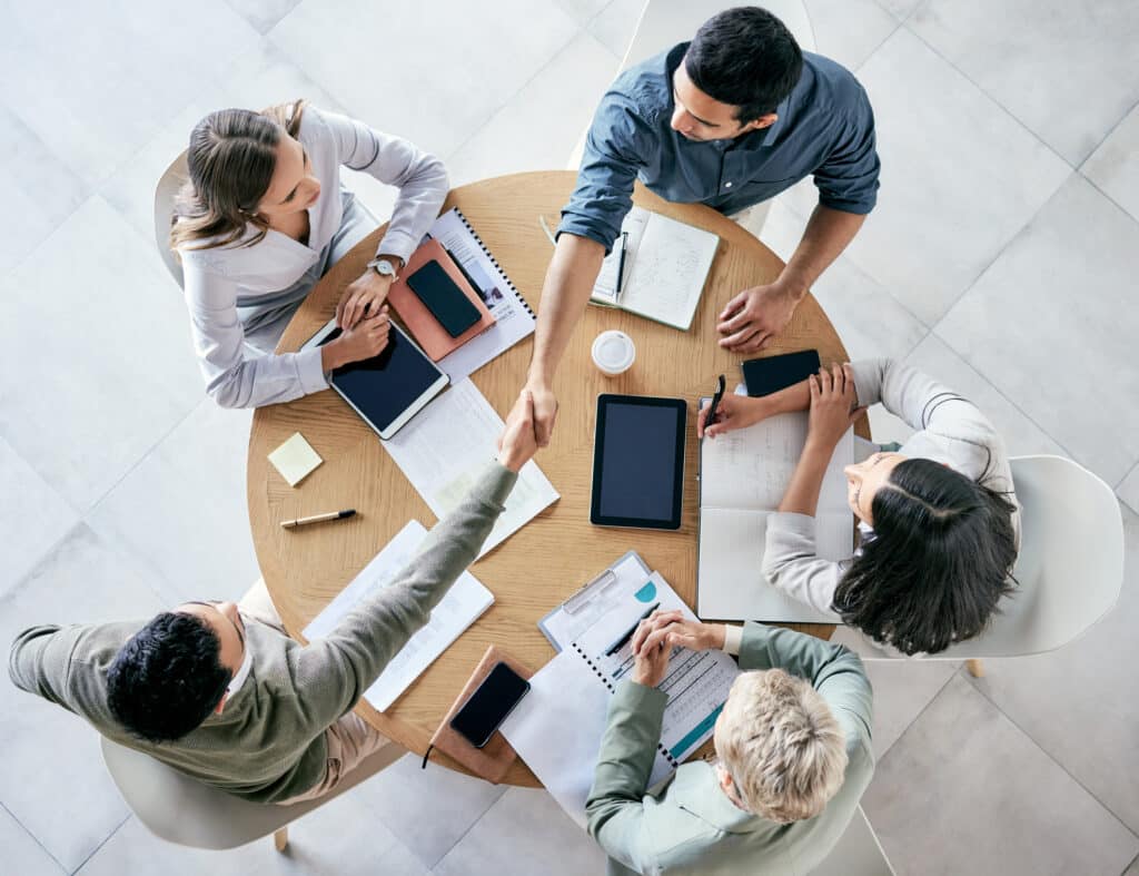 Shot of businessmen shaking hands during a team meeting in a modern office